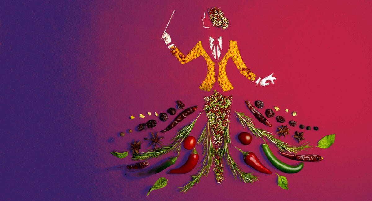 Colorful spices, herbs, and vegetables arranged in the shape of a woman conductor in formal attire